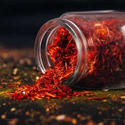 Saffron spice in an open glass jar on dark black background. Seasonings for food. Close-up.